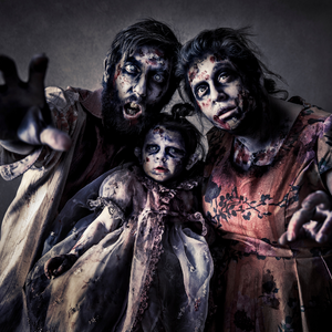 A man and woman with a baby are dressed up like zombies