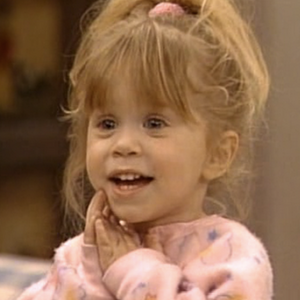 Michelle Tanner from Full House as a toddler, holding her hands under her chin