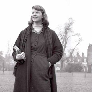 Black and white photo of Sylvia Plath, holding a book with a building behind her