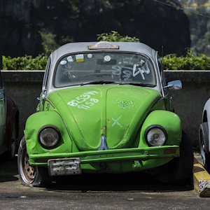 A beat up green Volkswagen beetle