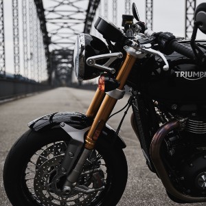A black Triumph motorcycle parked on a bridge