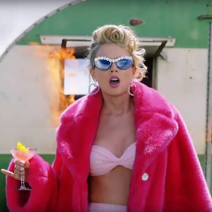 Screen grab from Taylor Swift's You Need to Calm Down music video, with Taylor rocking a pink fur coat and sunglasses and holding a martini
