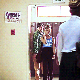 Buffy wearing a shiny blue tank top with a white spiral on the front and Xander wearing a shiny green print button-up long-sleeved shirt