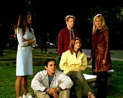 Cordelia, Oz, and Buffy stand behind a seated Xander and Willow and stare at the ruins of Sunnydale High