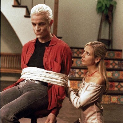 Buffy kneels while tying Spike to a chair