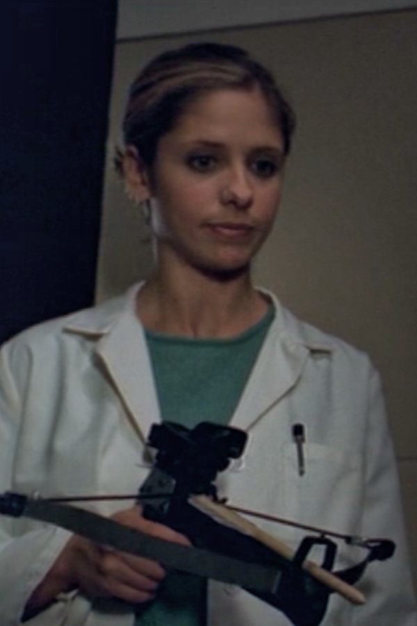Buffy wears a lab coat and holds a crossbow.