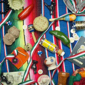 Various items representative of Mexican culture on a brightly colored blanket.