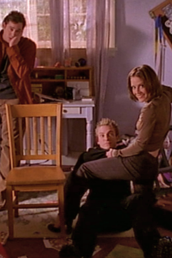 Xander holds his slapped face as Anya is about to punch Andrea in a good-cop, bad-cop scenario in Buffy's bedroom.