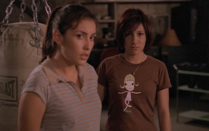 Kennedy, a brunette wearing a striped cropped sleeve polo, and Chloe, a brunette wearing a brown shirt featuring a cartoon girl