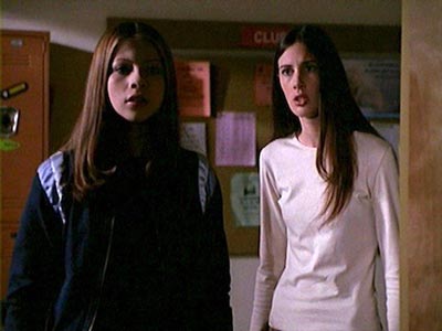 Dawn and Amanda, both with long brown hair, staring at something scary down the high school hallway