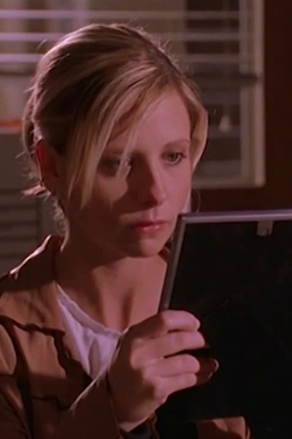 Buffy holding a picture frame and staring at it sadly