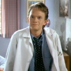 Neil Patrick Harris, as Doogie Howser, wears a lab coat and loosened tie while smiling wistfully