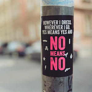 Sticker on a pole that reads "however I dress, wherever I go, yes means yes and no means no"