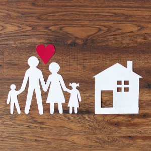 Paper doll family (mom, dad, and two children) with a red heart above them and a paper cut out house next to them