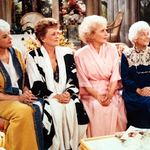 Cast of Golden Girls (Blanche, Dorothy, Rose, and Sophia) sitting on a couch in their robes