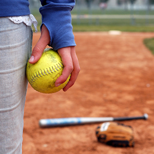 A girl holds a softball on the infield diamond.