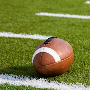 A football sitting on the grass of a football field.