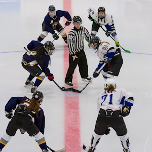 Hockey referee standing between 3 vs 3 hockey players facing off