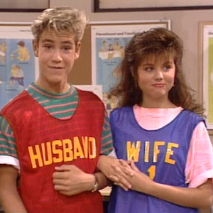 Zack and Kelly wearing shirts that say "husband" and "wife" from Saved By the Bell.