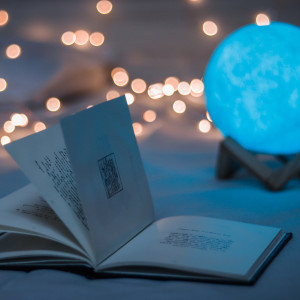 Open book with moving pages in front of a glowing blue sphere and twinkle lights