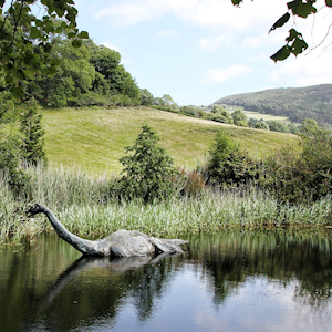 A loch in Scotland with Nessie the Loch Ness Monster standing in the water.