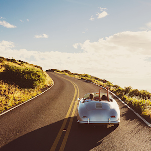 Happy Couple Driving on Country Road in Classic Vintage Sports Car