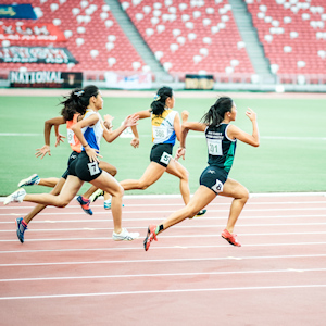 Women running in a race on a track in a stadium