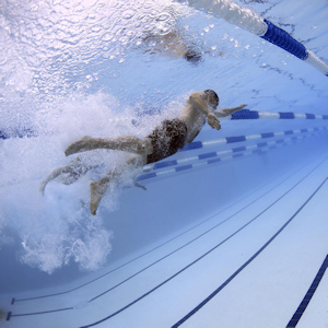 A man swimming underwater in lane in a pool