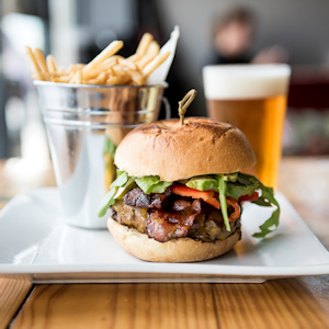 A burger, beer, and bucket of fries on a plate.