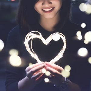 Woman smiling and holding heart-shaped object