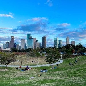 The downtown Houston skyline behind a park with cyclists
