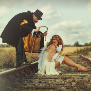 An old-timey villain ties a woman up on to train tracks