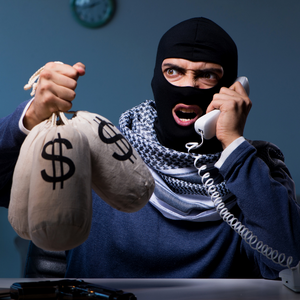 A kidnapper in a mask on the phone holding bags of money