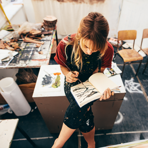 Girl in art studio painting in a notepad