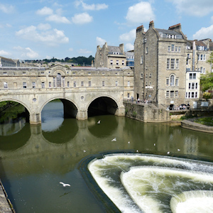 A bridge and water next to an old building in Bath, England