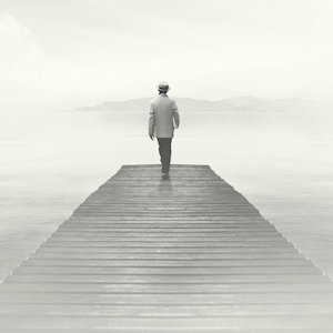 A man walking to the edge of a pier that fades into the mist