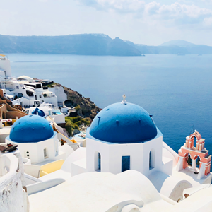 Ocean and skyline of Santorini, Greece with white buildings and blue dome roofs 