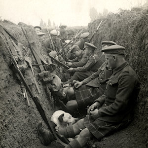 B&W image of men sitting in a trench with rifles