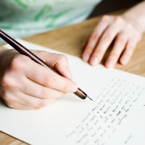 Close up of a person's hands while writing a letter