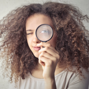 Woman holding a magnifying glass up to one eye