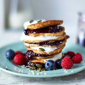 Stack of pancakes with fruit and whipped cream