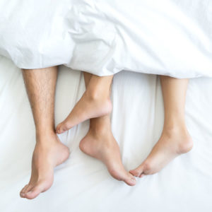 two pairs of feet showing under covers