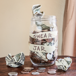 A swear jar with money stuffed inside and all around it