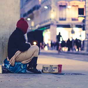 A person sits on the side of the rode with a sign