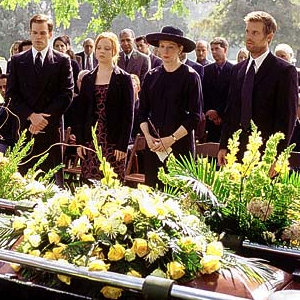 The characters from Six Feet Under standing by a coffin outside during a funeral