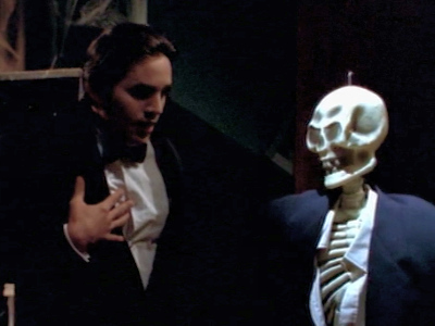 Xander in a tux getting scared by a skeleton in a tux