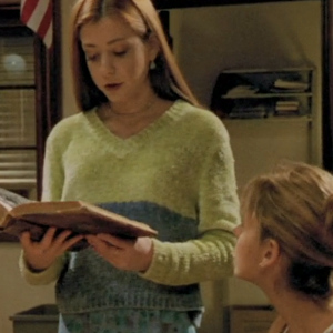 Willow wears a lime green sweater and holds a book