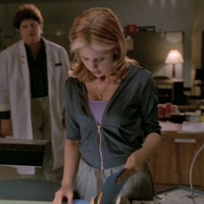 Buffy reading something at a desk in the clinic she broke into as a nurse catches her.
