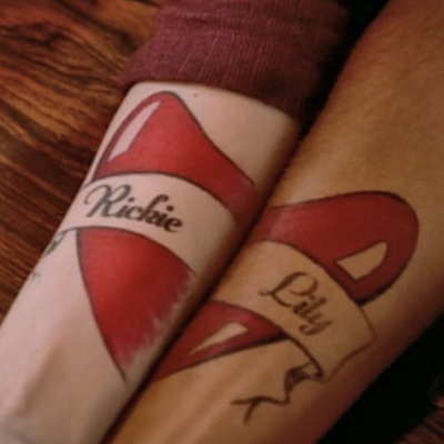 Two forearms each with half of a heart tattoo that says "Richie" and "Lily"