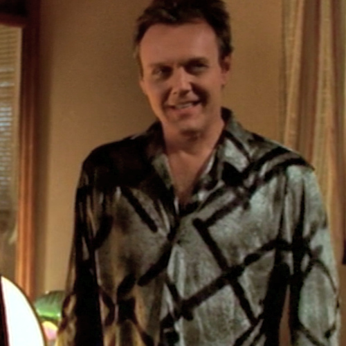 Giles wearing a silky brightly patterned shirt.